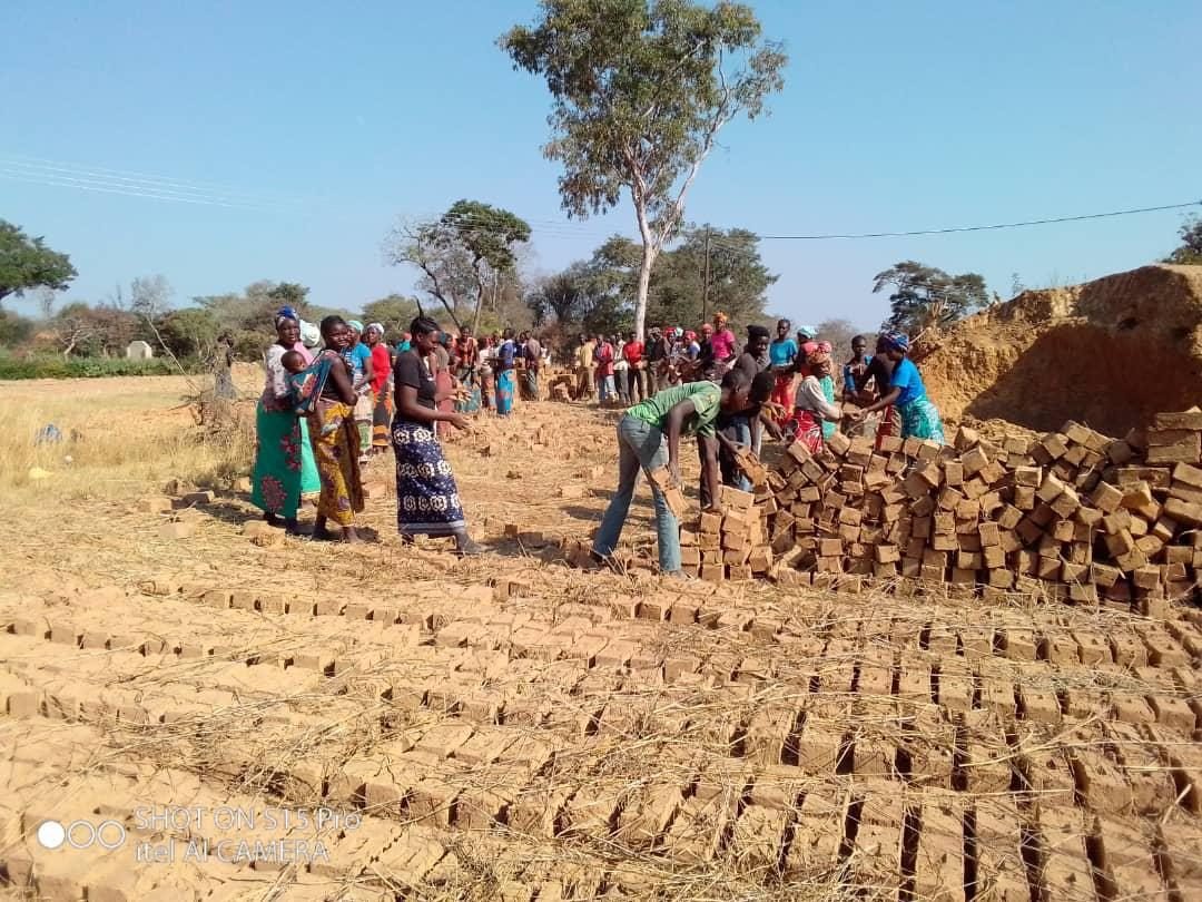 Community members of Simooya working together to mould and stack bricks